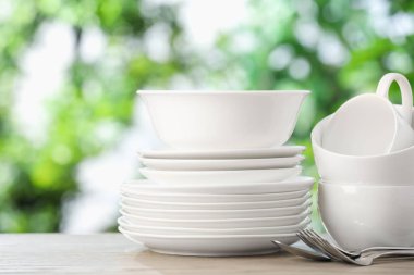 Ahşap masada, bulanık yeşil arka planda farklı temiz tabaklar.