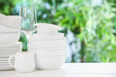 Beyaz masadaki farklı temiz tabaklar, bulanık yeşil arkaplan, metin için boşluk