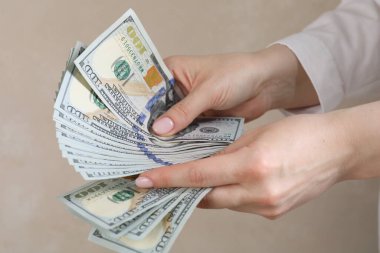 Bej arka planda dolar sayan bir kadın, yakın plan.