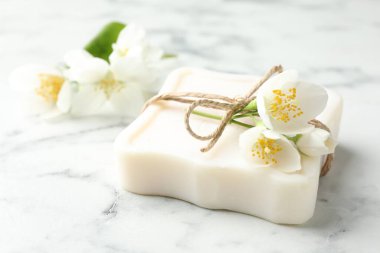 Sabun çubuğu ve yasemin çiçekleri beyaz mermer masada, yakın plan.