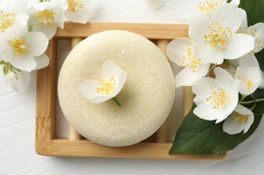 Sabun çubuğu ve yasemin çiçekleri beyaz ahşap masada, düz yatıyordu.