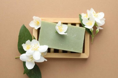 Açık kahverengi arka planda sabun ve yasemin çiçekleri, düz uzanmış