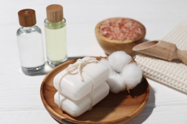 Sabun barları, kozmetik ürünleri, beyaz ahşap masada havlu ve pamuk çiçeği, yakın plan.