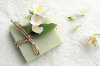 Sabun çubuğu ve yasemin çiçekleri havluda, düz yatar