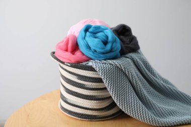 Yumuşak yün ve örgü ipliği sepetin içinde açık gri arka plana karşı ahşap masa üzerinde