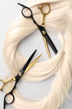 Sarı saç tokası ve makas açık gri arka planda, düz yatıyordu.