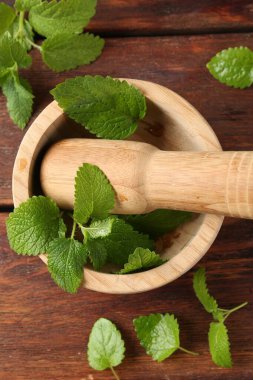 Taze limon merhemi yaprakları, ahşap masa üzerinde tokmak ve harç, düz uzanma