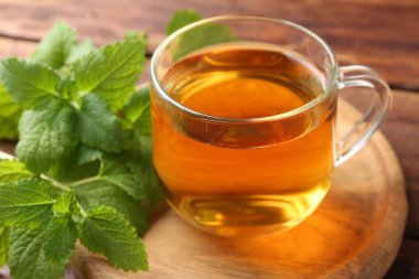 Cam bardakta Aromatik limon merhemi çayı ve masada taze yapraklar, yakın plan.