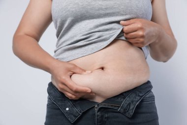 Hafif arka planda aşırı göbek yağı olan kadın, yakın plan. Aşırı kilolu