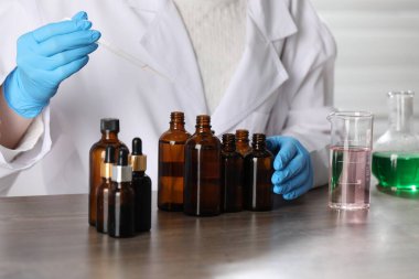 Laboratuardaki ahşap masada lüks parfüm üreten profesyonel parfümcü.