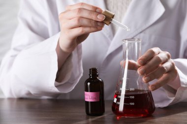 Laboratuardaki ahşap masada lüks parfüm üreten profesyonel parfümcü.