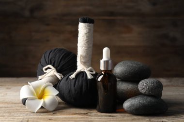 Kozmetik ürünler, spa taşları ve ahşap masada bitkisel torbalar, yakın çekim.