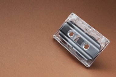 Kahverengi arka planda manyetik bantlı bir ses kaseti, yakın plan. Metin için boşluk