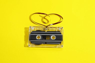 Sarı arkaplanda kalp şeklindeki manyetik bantlı bir ses kaseti.