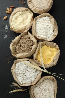Siyah masa üzerinde, kağıt torbalarda farklı tipte un, düz yerde.