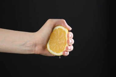 Siyah arka planda limon sıkan kadın, yakın plan.