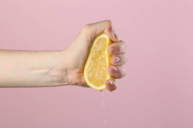 Pembe arka planda limon sıkan kadın, yakın plan.