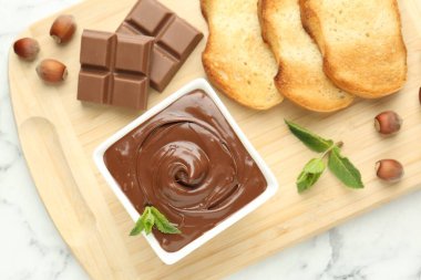 Lezzetli çikolata, parçalar, tost, nane ve fındık beyaz mermer masa, üst görünüm