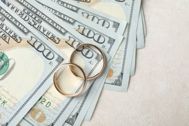 Beyaz masada iki altın alyans ve bir dolarlık banknotlar. Metin için boşluk