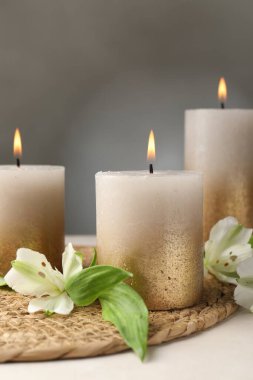 Beyaz masada yanan mumlar ve zambak çiçekleri, yakın plan.