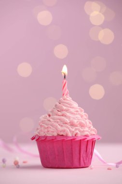 Masanın üzerinde, pembe arka planda, bulanık ışıklarla yanan mum. Metin için boşluk