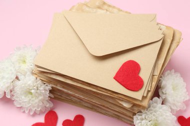 Pembe arka planda aşk mektupları, çiçekler ve kırmızı kalpler yığını.