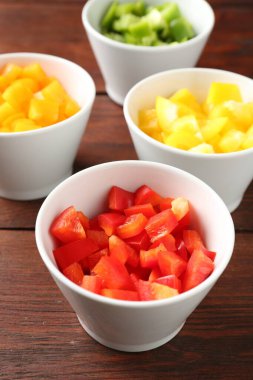 Tahta masadaki kaselerde taze dolmalık biberler, yakın plan.