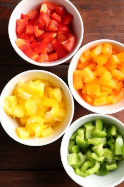 Taze renkli dolmalık biberler ahşap masadaki kaselerde, düz yatıyordu.