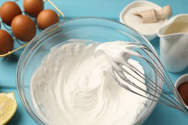 Açık mavi masada çırpılmış krema, yumurta ve diğer ürünler, yakın plan.