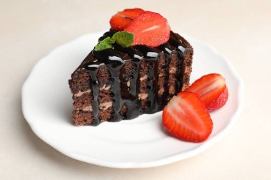 Bir parça çikolatalı kek, beyaz masada çilekli, yakın plan.