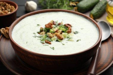 Siyah ahşap masada servis edilen dereotlu ve cevizli lezzetli salatalık çorbası.