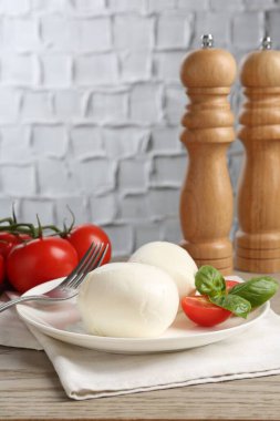 Lezzetli mozzarella peynir topları, domates ve fesleğen ahşap masada, yakın plan.