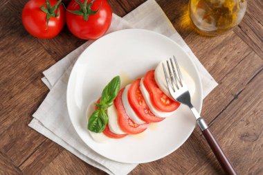 Lezzetli mozzarella, domates, yağ ve fesleğen ahşap masa, düz yatıyordu.