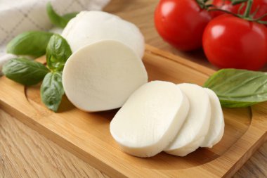 Lezzetli mozzarella, domates ve fesleğen ahşap masada, yakın plan.