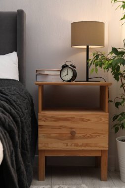 İçinde lamba, çalar saat ve yatağın yanında kitaplar olan komodin. İç tasarım