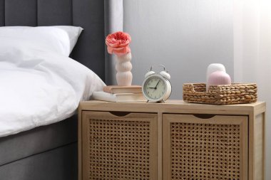 Yatağın yanında alarm saati ve dekorasyonu olan komodinin yanında.
