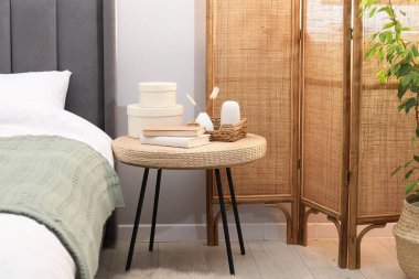 Yatağın yanında kitap ve dekor olan yan masa.