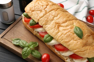 Mozarella peynirli, domatesli, fesleğenli, siyah ahşap masa, yakın plan.