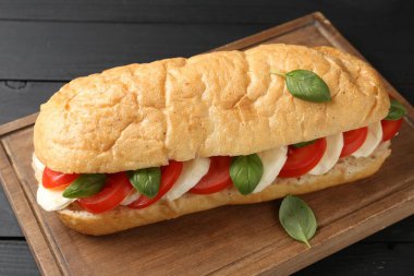 Mozarella peynirli, domatesli, fesleğenli, siyah ahşap masa, yakın plan.