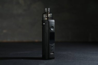 Koyu renkli masada gri arkaplana karşı elektronik sigara içme cihazı, yakın plan.
