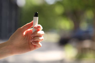 Dışarıda elektronik sigara içen genç bir kadın, yakın plan. Metin için boşluk