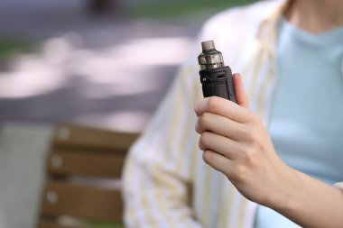Dışarıda elektronik sigara içen genç bir kadın, yakın plan. Metin için boşluk