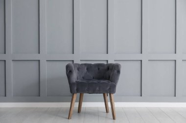 Açık gri duvarın yanında rahat bir koltuk.