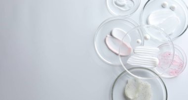 Petri kabında farklı kozmetik ürünleri, beyaz arka planda, düz yerde. Metin için boşluk