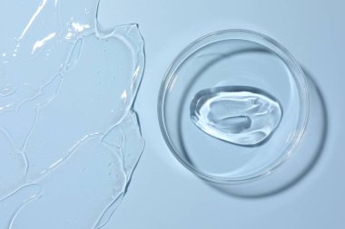 Petri kabında açık mavi arka planda kozmetik ürünü, üst görünüm