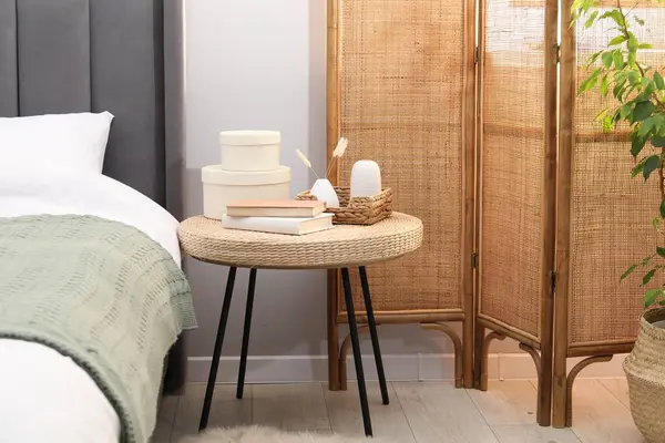 Yatağın yanında kitap ve dekor olan yan masa.