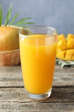 Bardakta lezzetli mango suyu ve ahşap masada taze meyve, yakın plan.