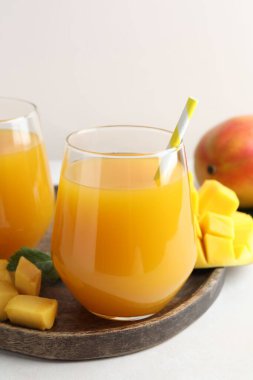 Bardakta lezzetli mango suyu ve beyaz masada taze meyve, yakın plan.