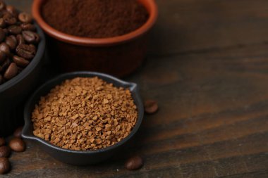 Tahta masadaki kaselerde farklı kahve ve fasulye türleri, yakın plan. Metin için boşluk