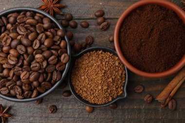 Farklı türde hazır kahve, fasulye ve baharatlar ahşap masada, düz yerde.